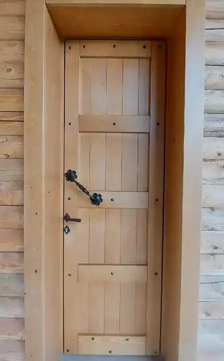 Porta in legno con doghe verticali e maniglia in ferro battuto